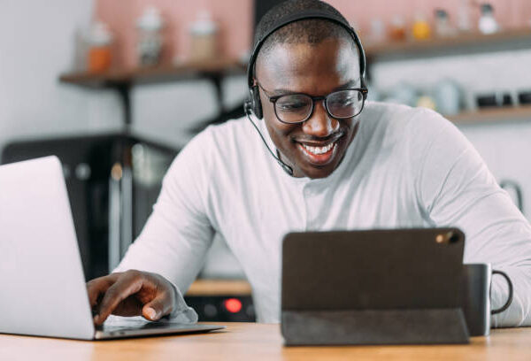 Shot of handsome young businessman working from home. Photo of a young african-american man using a laptop, digital tablet and headset while working at home.